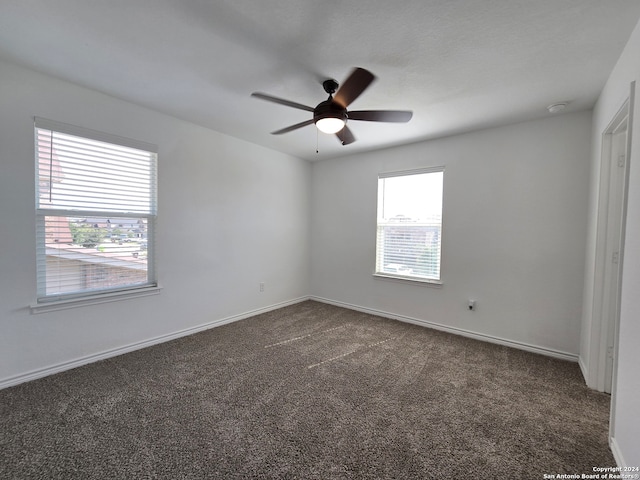 carpeted spare room featuring ceiling fan and plenty of natural light