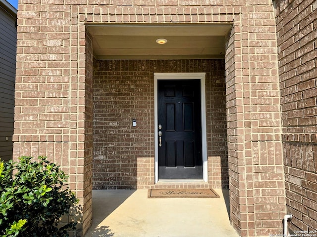 view of exterior entry featuring brick siding