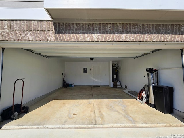 garage featuring water heater, driveway, and electric panel