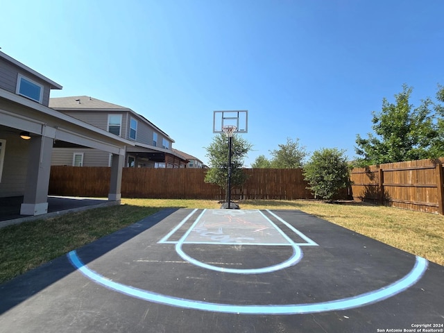 view of sport court with basketball court, a fenced backyard, and a yard