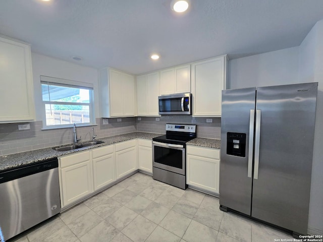 kitchen with dark stone counters, appliances with stainless steel finishes, a sink, and tasteful backsplash