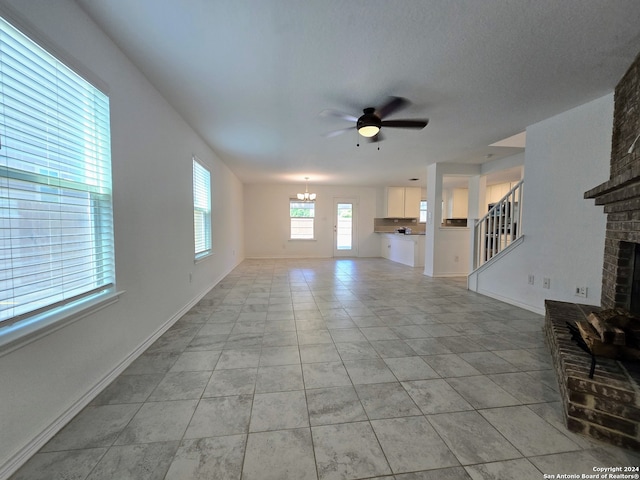 unfurnished living room with light tile patterned floors, ceiling fan, and a brick fireplace