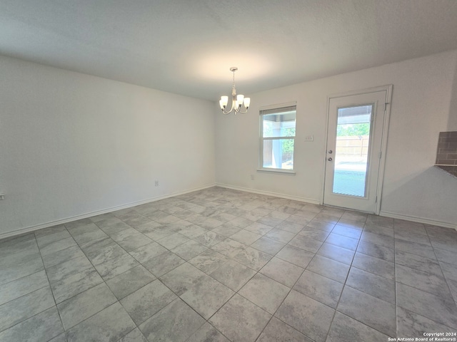 empty room featuring a notable chandelier and light tile patterned floors