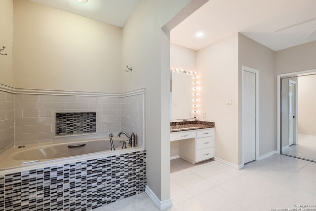 bathroom with tile patterned floors, vanity, and a relaxing tiled tub