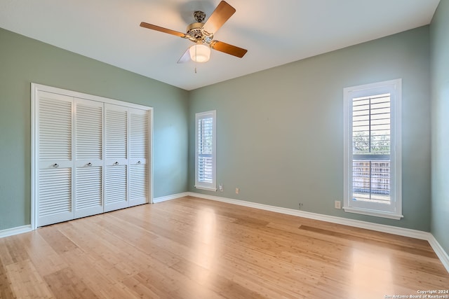 unfurnished bedroom featuring ceiling fan, multiple windows, and light wood-type flooring