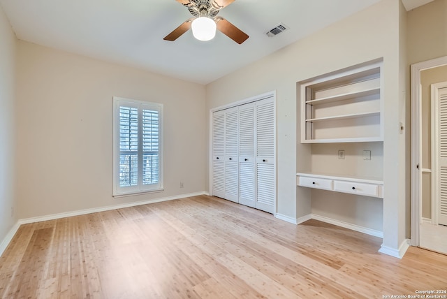 unfurnished bedroom featuring ceiling fan, light hardwood / wood-style floors, and built in desk