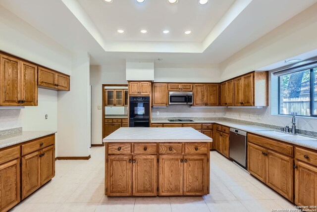 kitchen with light tile patterned flooring, a raised ceiling, sink, and black appliances