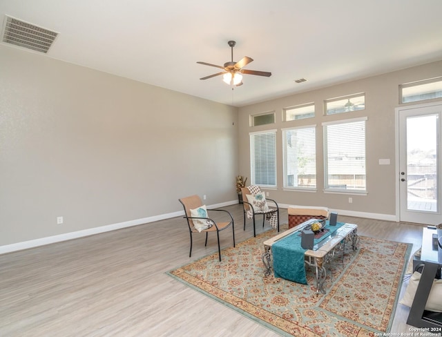 living area featuring baseboards, visible vents, ceiling fan, and wood finished floors