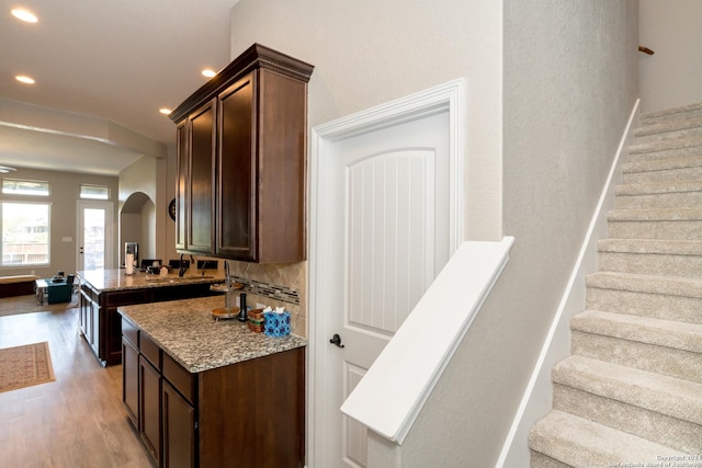 kitchen with light wood finished floors, decorative backsplash, and dark brown cabinets