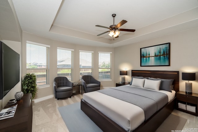 bedroom featuring ceiling fan, light carpet, and a raised ceiling