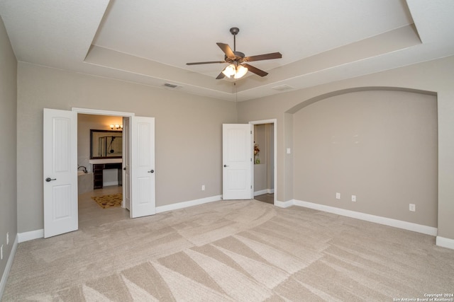 unfurnished bedroom featuring a tray ceiling, visible vents, and baseboards