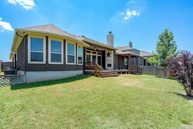 rear view of house featuring a deck, fence, a ceiling fan, a yard, and a chimney