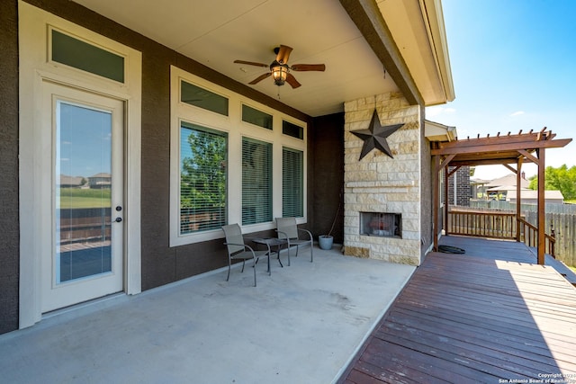 view of patio with a ceiling fan, an outdoor stone fireplace, and a pergola