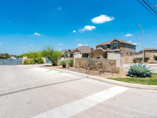 view of road featuring street lighting, a residential view, a gate, and curbs