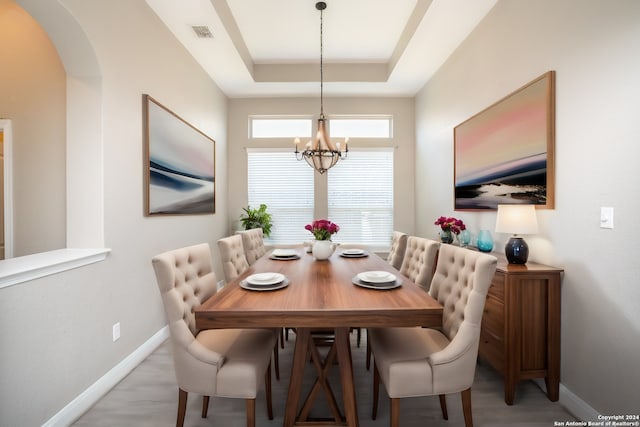 dining area with arched walkways, baseboards, a raised ceiling, and a notable chandelier