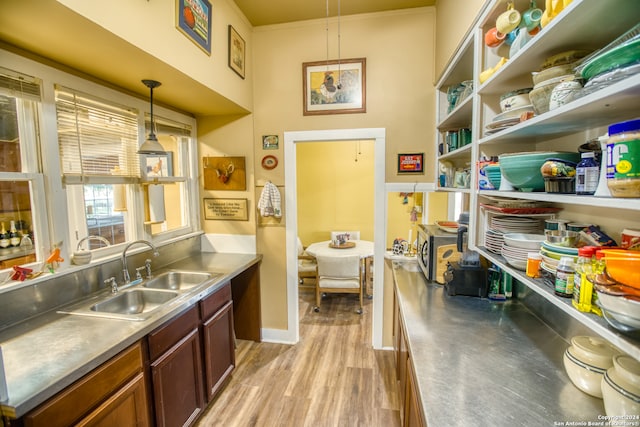 kitchen with sink, stainless steel counters, light hardwood / wood-style flooring, and pendant lighting