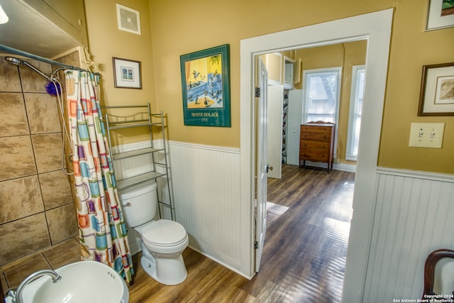 bathroom with hardwood / wood-style flooring, a shower with curtain, and toilet