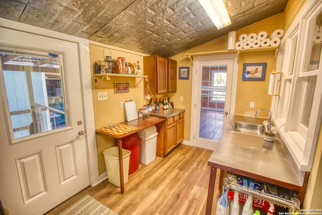 kitchen with sink, vaulted ceiling, and light wood-type flooring