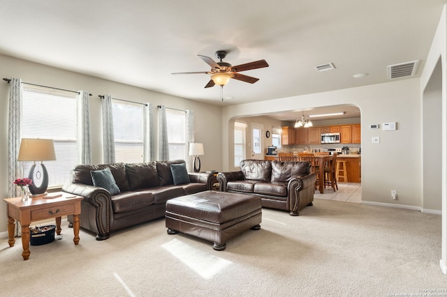 living room featuring light tile patterned flooring and ceiling fan with notable chandelier