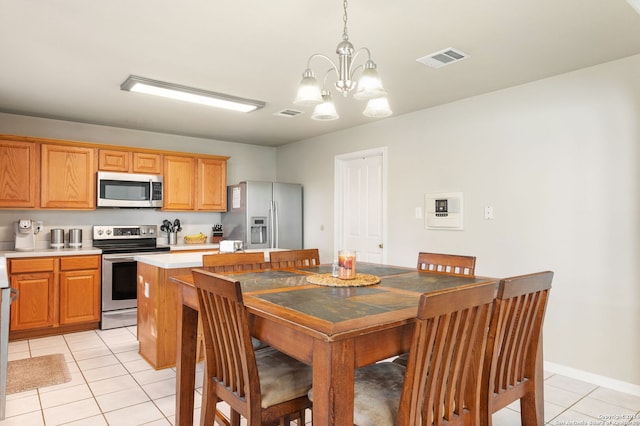 kitchen with a notable chandelier, a kitchen island, light tile patterned floors, and stainless steel appliances