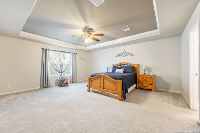 carpeted bedroom with ceiling fan and a raised ceiling