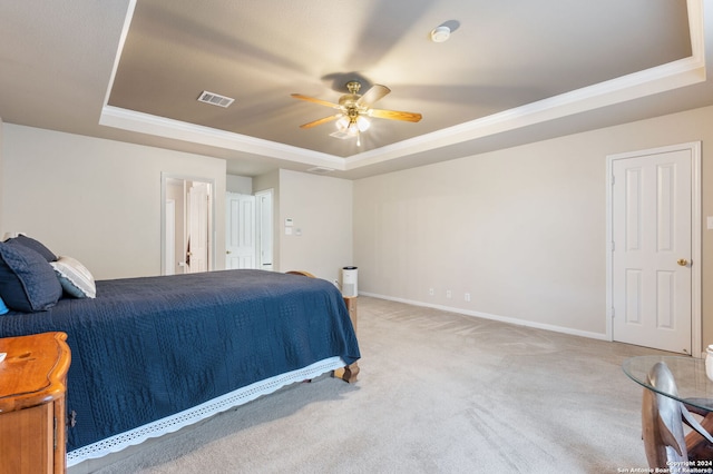 carpeted bedroom featuring a tray ceiling and ceiling fan