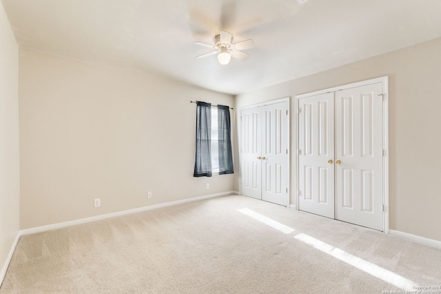 unfurnished bedroom with ceiling fan, carpet, and two closets