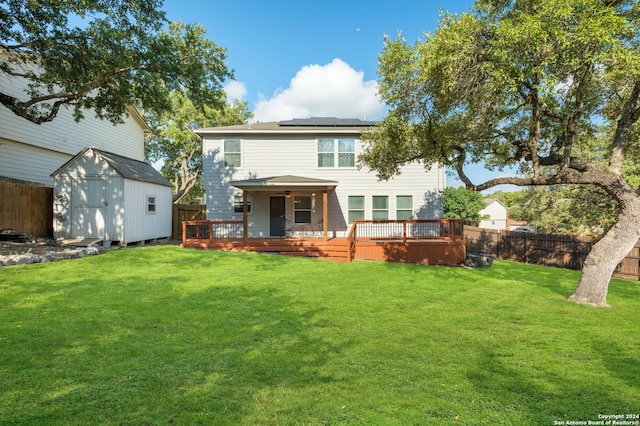 back of property with a storage unit, a wooden deck, and a lawn