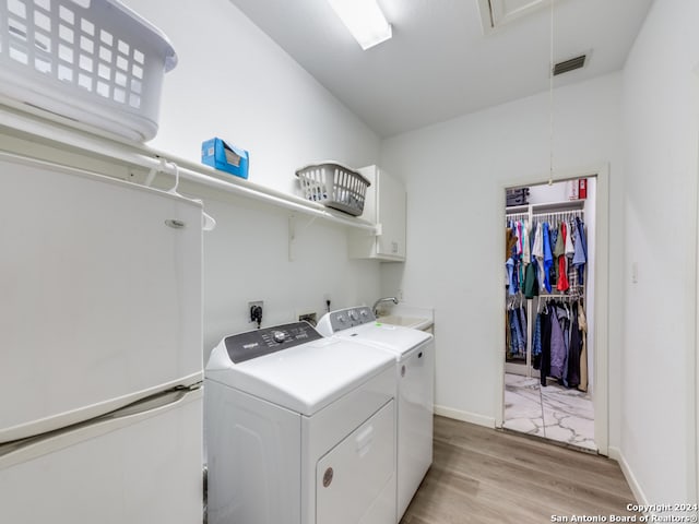 laundry room featuring light hardwood / wood-style flooring, cabinets, sink, and independent washer and dryer