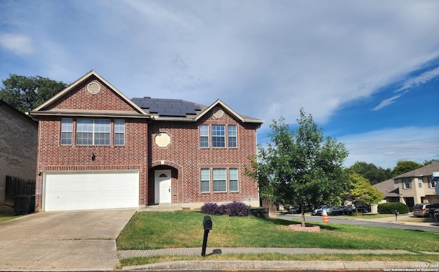 view of front of house featuring brick siding, a front yard, roof mounted solar panels, a garage, and driveway