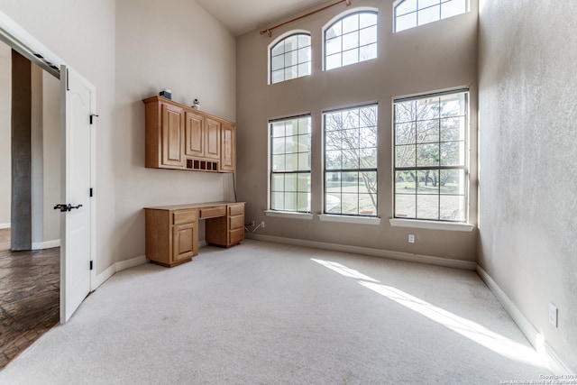 carpeted living room featuring a wealth of natural light and a towering ceiling