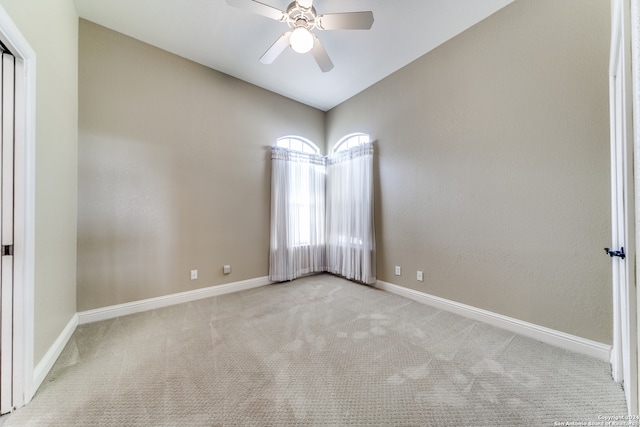 spare room with ceiling fan, vaulted ceiling, and light carpet