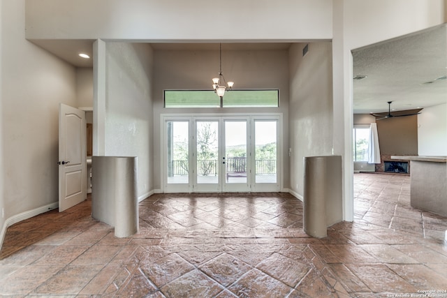 tiled entryway with a high ceiling, a notable chandelier, and a healthy amount of sunlight