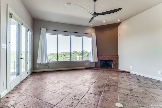 unfurnished living room with ceiling fan, french doors, a tiled fireplace, and tile patterned floors