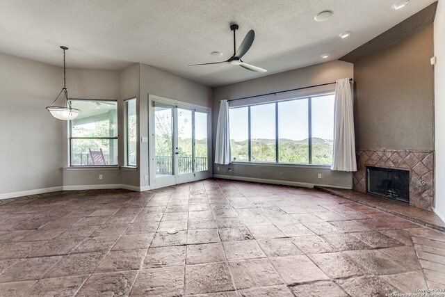 unfurnished living room featuring tile patterned flooring, ceiling fan, and a fireplace