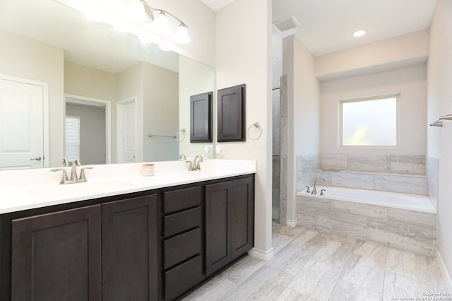 bathroom featuring vanity and a relaxing tiled tub