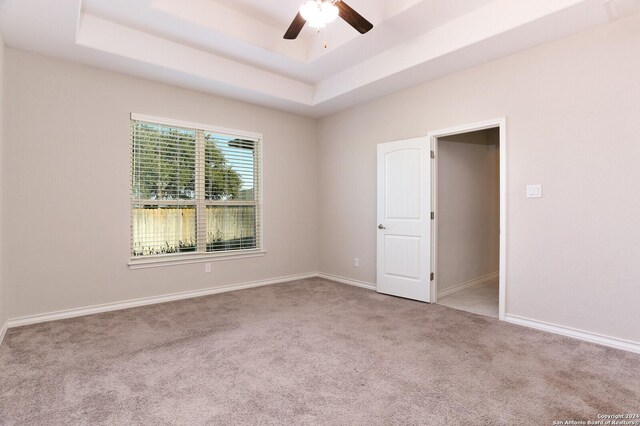 spare room featuring ceiling fan, a raised ceiling, and light carpet