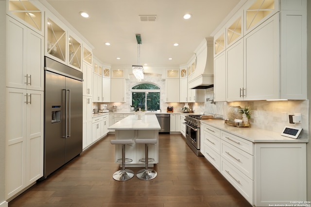 kitchen with high end appliances, premium range hood, dark hardwood / wood-style flooring, and backsplash