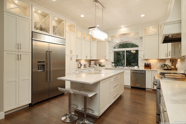 kitchen featuring backsplash, stainless steel appliances, dark hardwood / wood-style floors, a kitchen island, and crown molding