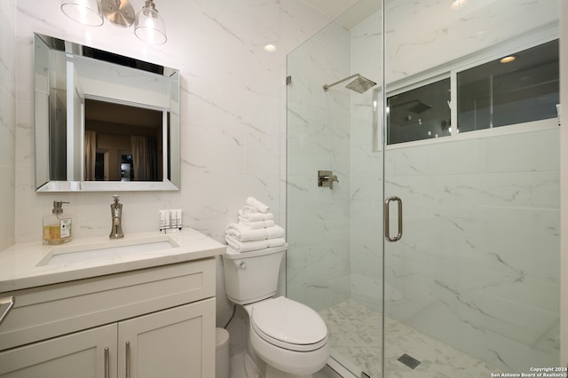 bathroom with tile walls, vanity, walk in shower, and toilet