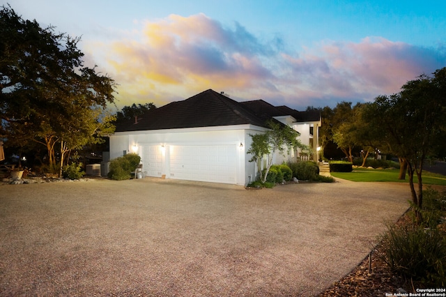 property exterior at dusk featuring central AC and a garage