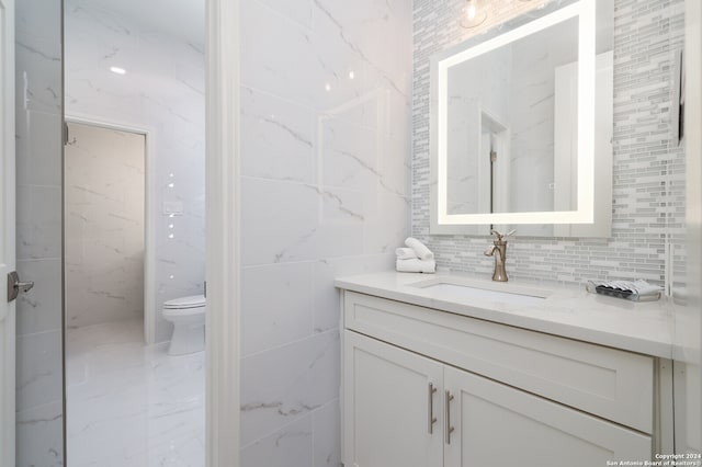 bathroom featuring tasteful backsplash, toilet, vanity, and tile walls