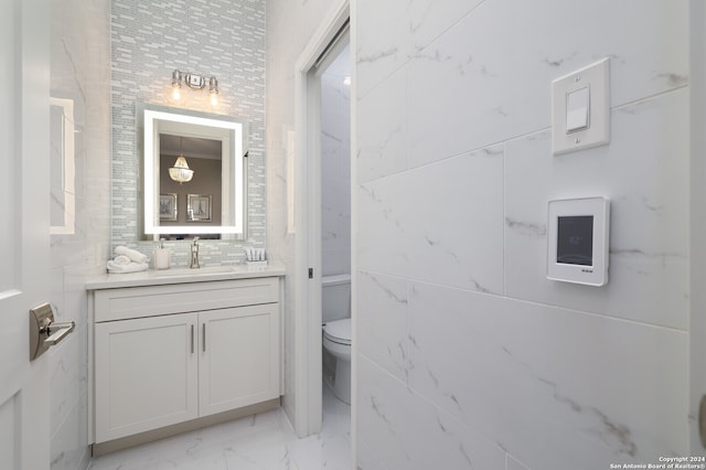 bathroom with tile walls, toilet, vanity, and tile patterned floors