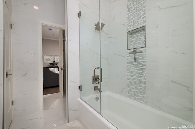 bathroom with bath / shower combo with glass door, ornamental molding, and tile walls