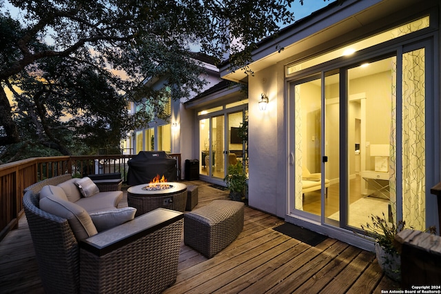 deck at dusk with an outdoor living space with a fire pit and a grill