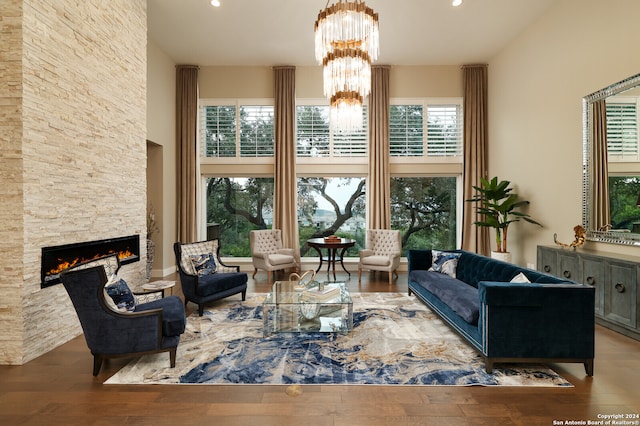 living room featuring hardwood / wood-style flooring, a notable chandelier, a healthy amount of sunlight, and a stone fireplace