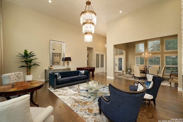 living room with hardwood / wood-style floors, a towering ceiling, and a chandelier