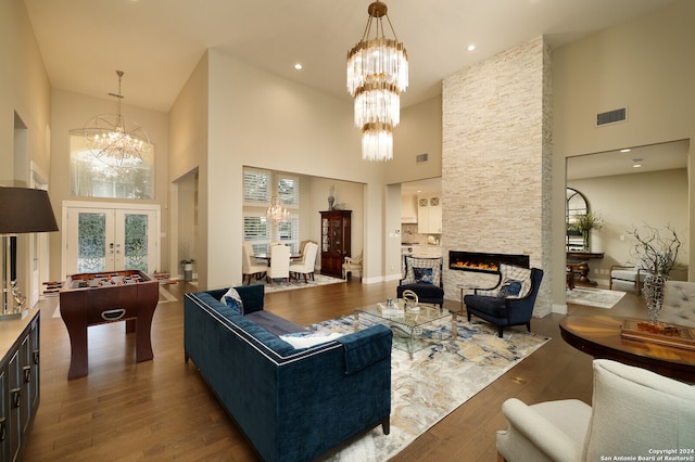 living room featuring a fireplace, a chandelier, hardwood / wood-style flooring, and a towering ceiling