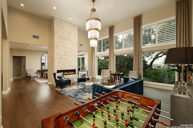 recreation room with hardwood / wood-style flooring, a fireplace, plenty of natural light, and a high ceiling