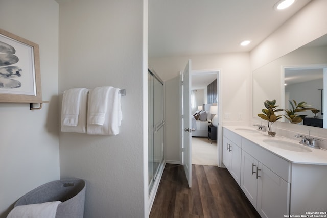 bathroom featuring hardwood / wood-style flooring, double vanity, and a shower with shower door